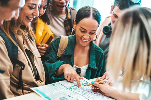 Student pointing out a destination on a map to tourists.